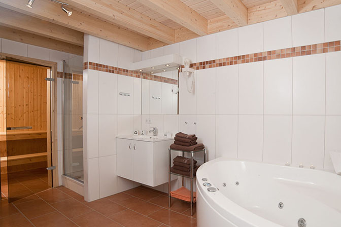 das geräumige Badezimmer mit angeschlossener Sauna und großer Badewanne
